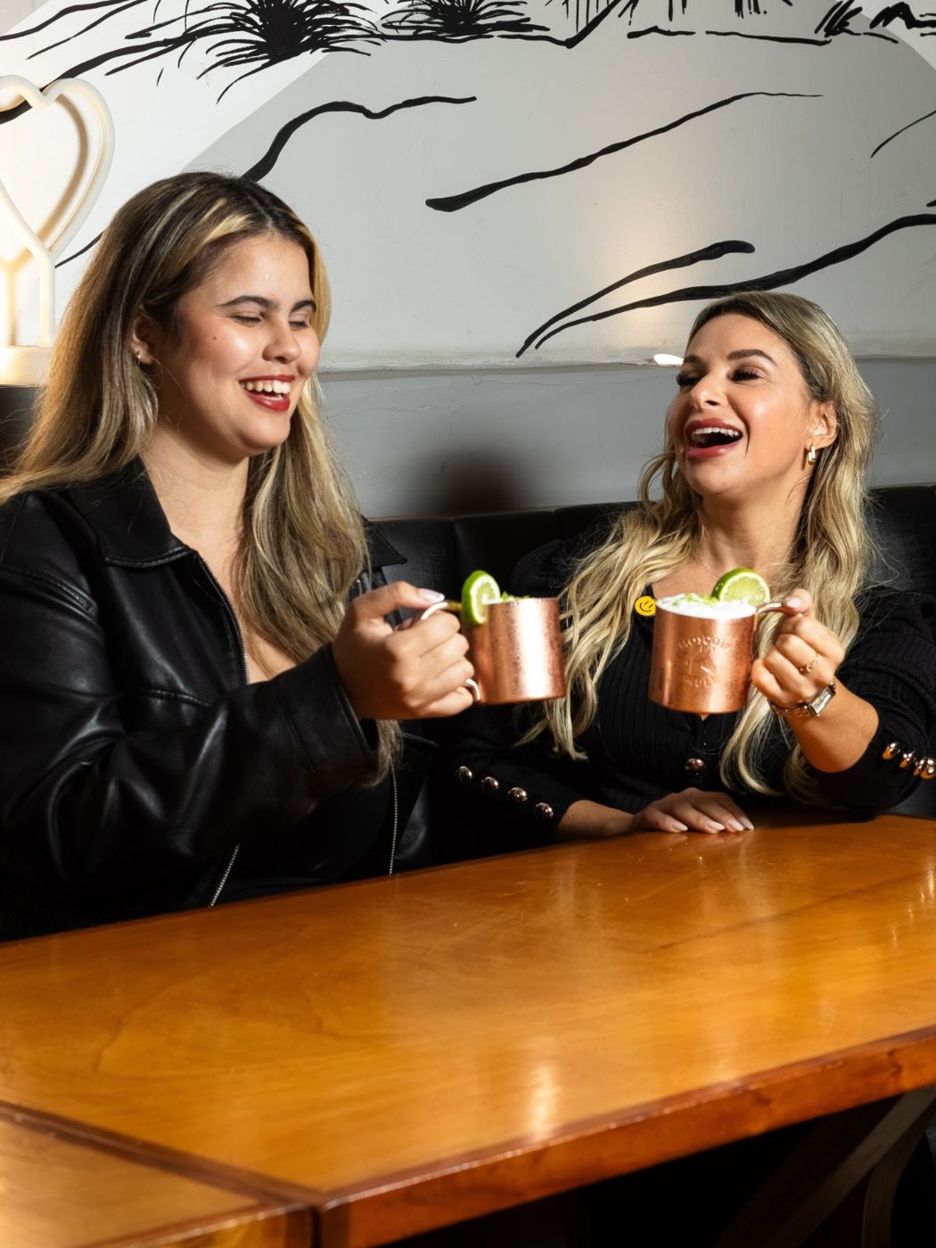 Duas amigas brindando com drinks no salão