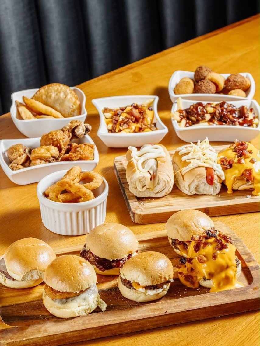 Tábua do rodízio com mini burgers, mini hot dogs, pastéis, batatas e anel de cebola