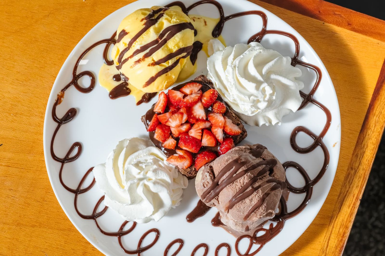 Brownie com morangos, sorvetes e chantilly com calda de chocolate